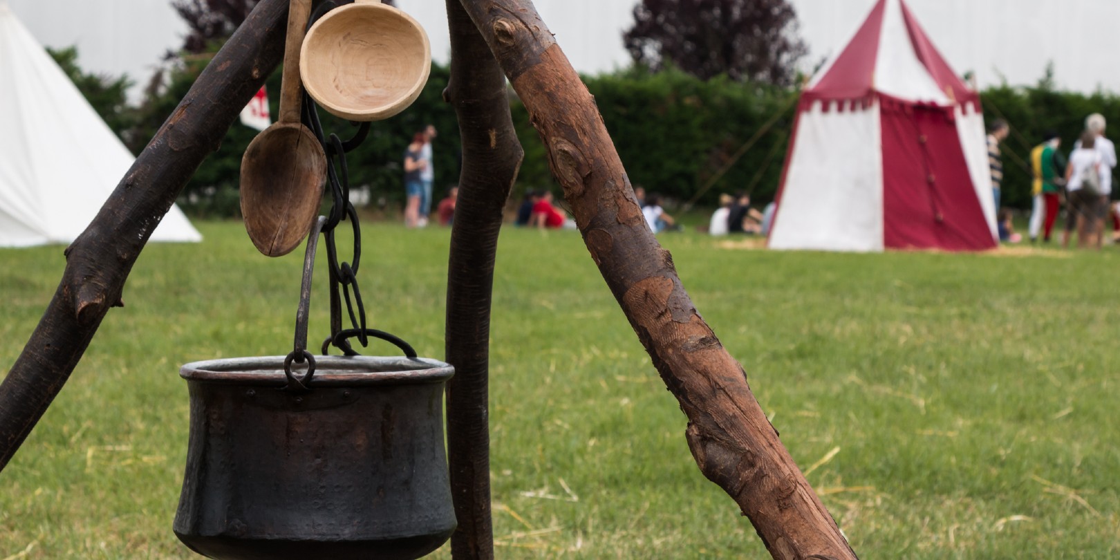 Black Pettle and Wooden Spoon after Bonfire on Tripod, White and Red Tent in background